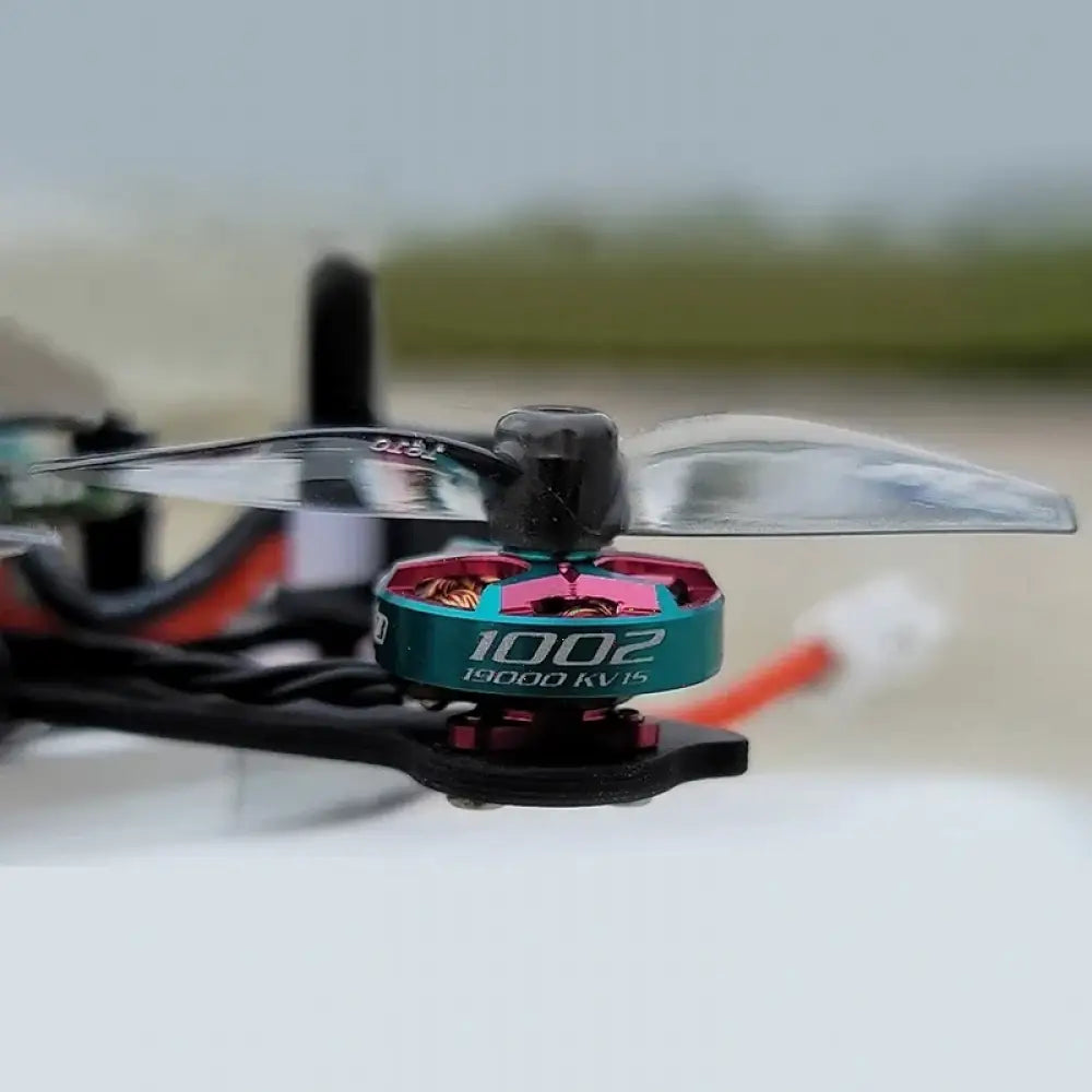 Hélice Gemfan 1610 transparente de 40mm à 2 pales sur un moteur de drone teal et rose.